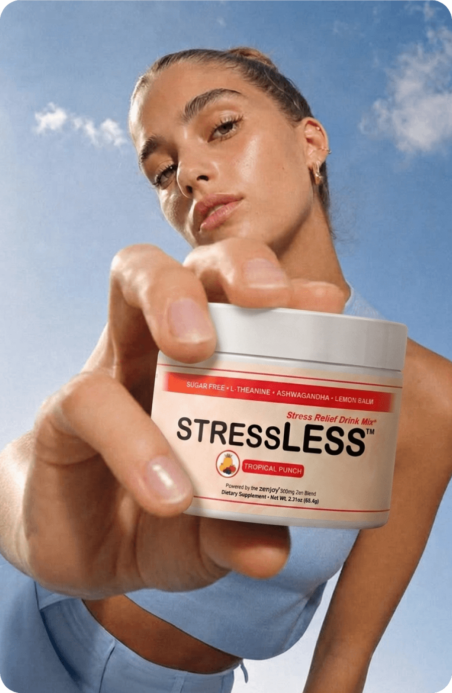 A woman holding up a tub of StressLESS against the sky