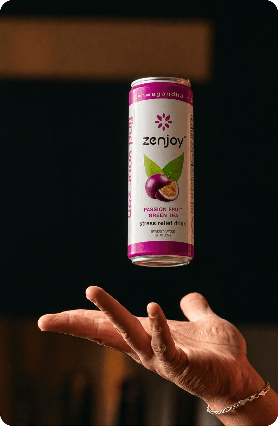 A Passion Fruit Green Tea can tossed above an open hand